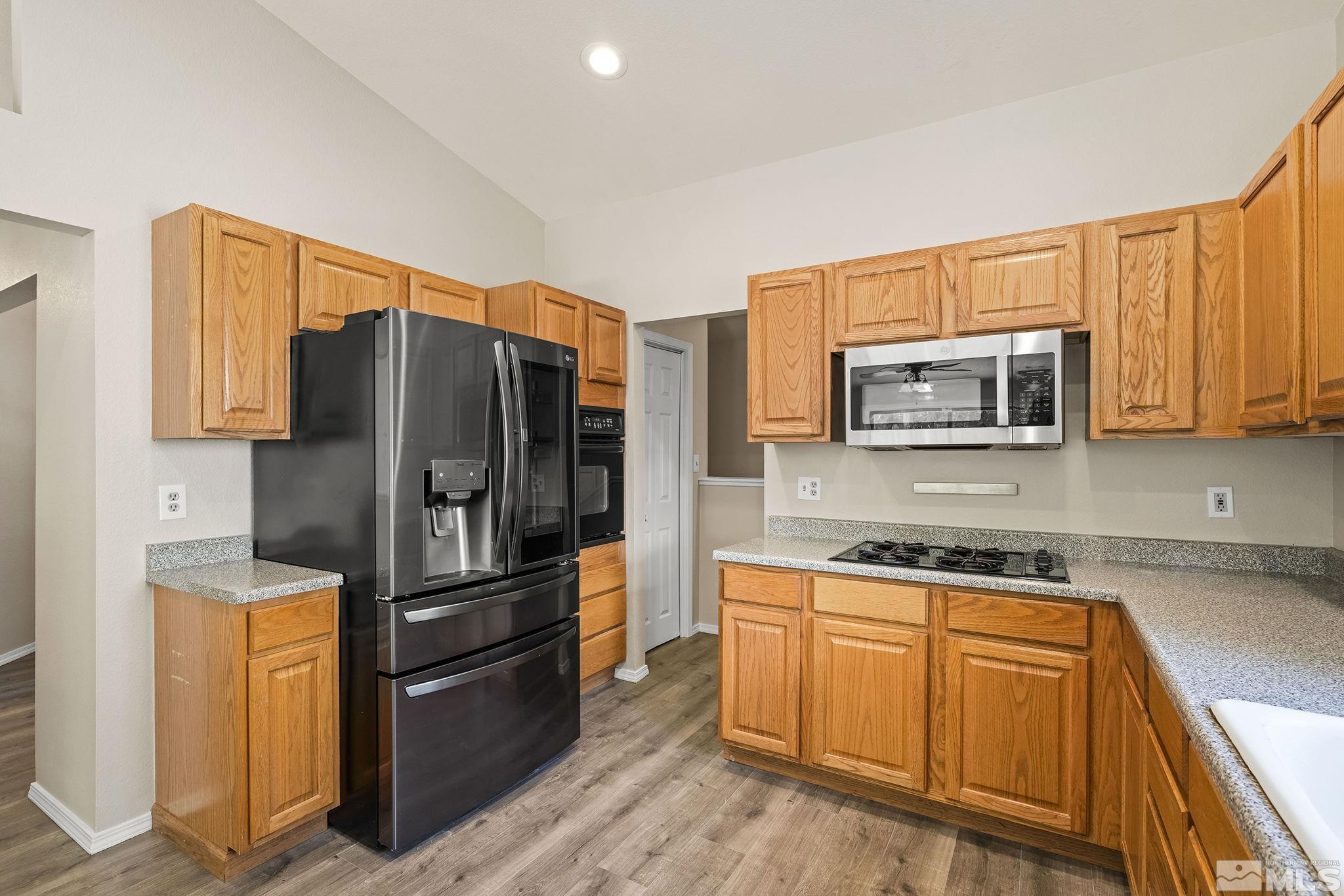 540 Citadel Road Reno, NV 89503 - Photo 12 of 30 a kitchen with granite countertop wooden cabinets a refrigerator and a stove top oven