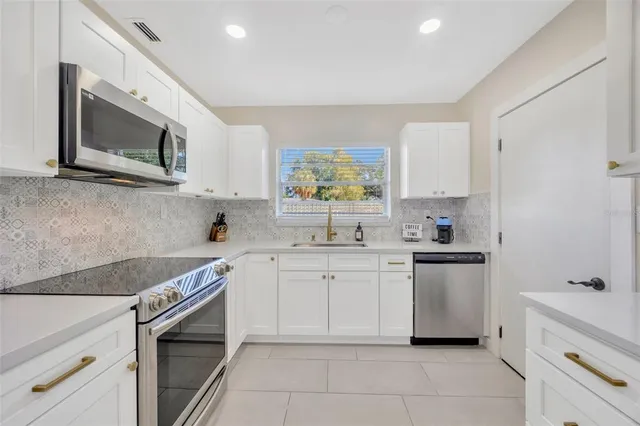 a kitchen with white cabinets and appliances
