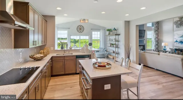 a kitchen with a stove a sink a kitchen island with chairs and wooden floor