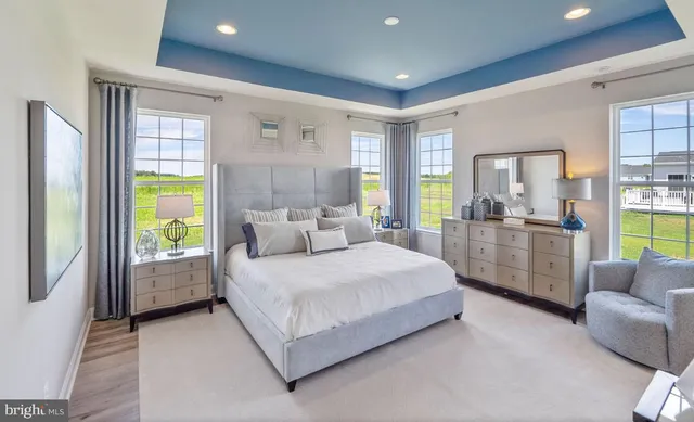 a spacious bedroom with a bed and glass walk in closet