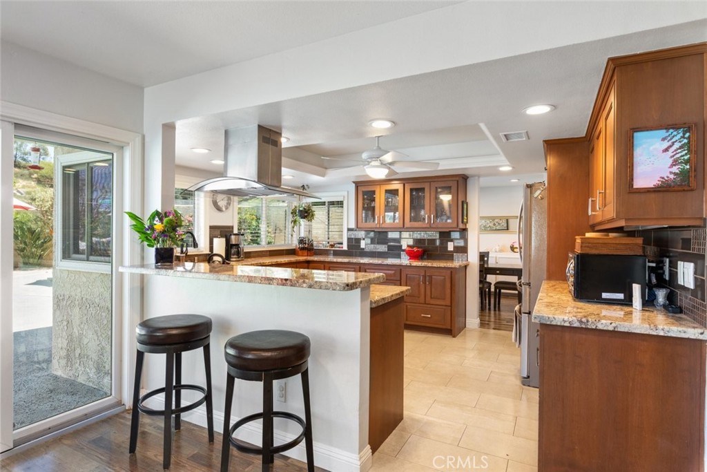 30198 La Primavera Street Temecula, CA 92592 - Photo 13 of 50 a kitchen with stainless steel appliances kitchen island granite countertop a table chairs and a refrigerator