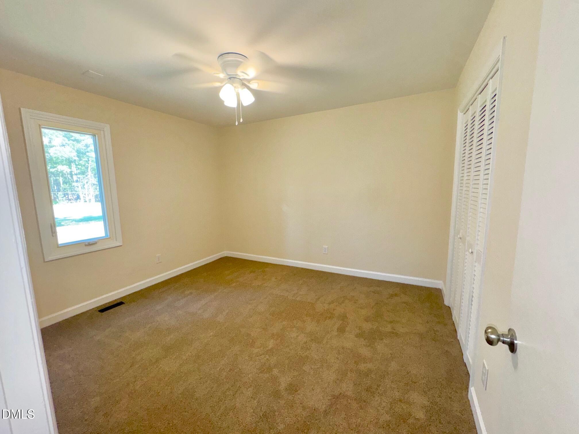 1720 Ross Mill Road Henderson, NC 27537 - Photo 26 of 42 an empty room with a chandelier fan and windows