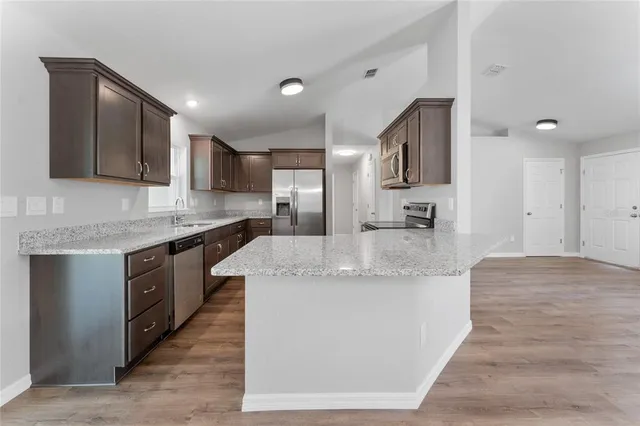 a large kitchen with stainless steel appliances granite countertop a large counter top and a sink
