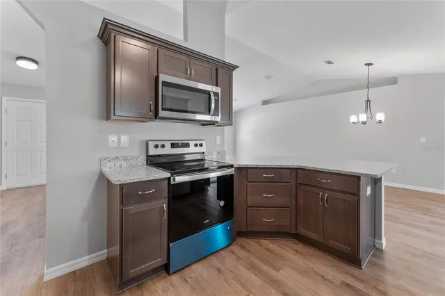 a kitchen with stainless steel appliances granite countertop a stove a sink and a microwave