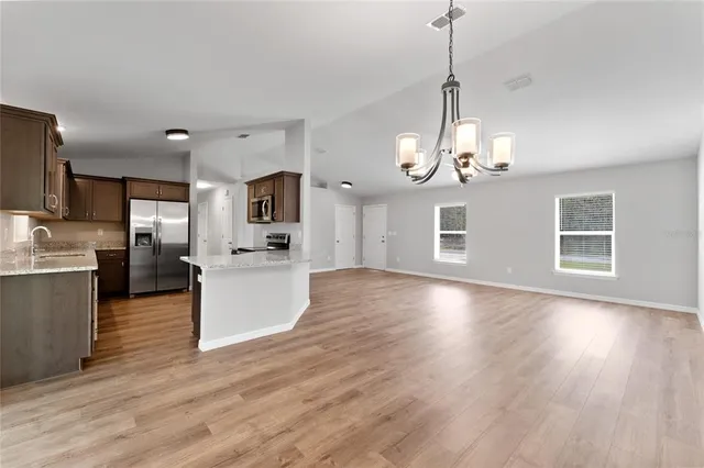 a view of a kitchen with granite countertop wooden floor stainless steel appliances and a counter space