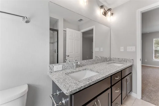 a bathroom with a granite countertop sink a toilet and a mirror