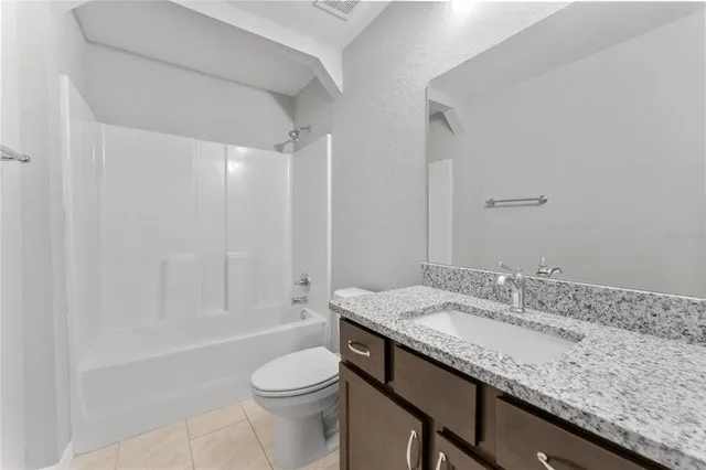 a bathroom with a granite countertop sink a toilet and shower