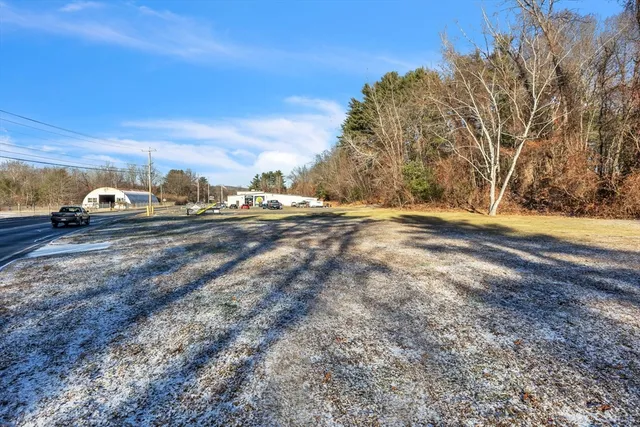 a view of dirt yard with a car parked on the roadside