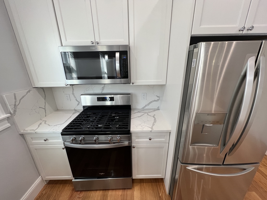 29 Alpine Street, Unit 1 Somerville, MA 02144 - Photo 9 of 33 a kitchen with stainless steel appliances a stove a refrigerator and cabinets