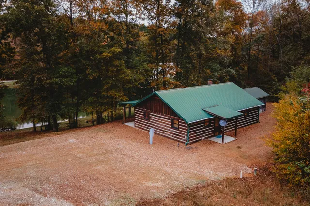 a small barn with a small yard and large trees