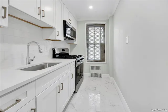a kitchen with white cabinets and sink