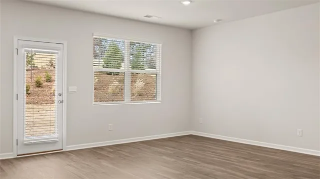 an empty room with wooden floor and windows