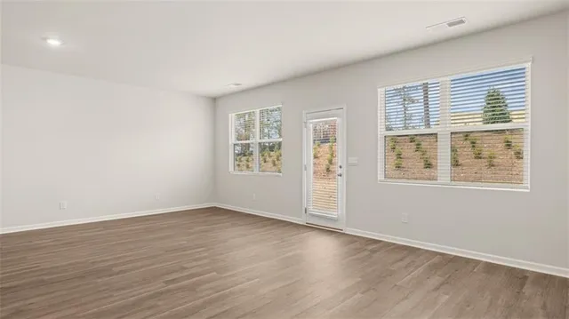 an empty room with wooden floor and windows