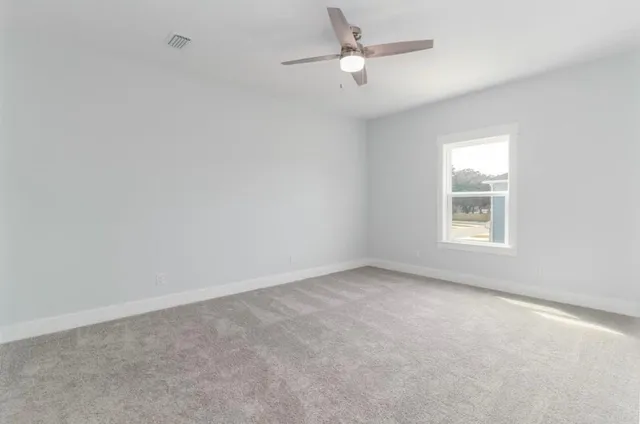 an empty room with a window and a ceiling fan