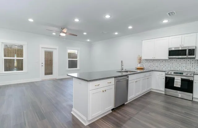 a kitchen with granite countertop a stove top oven a sink and dishwasher with wooden floor