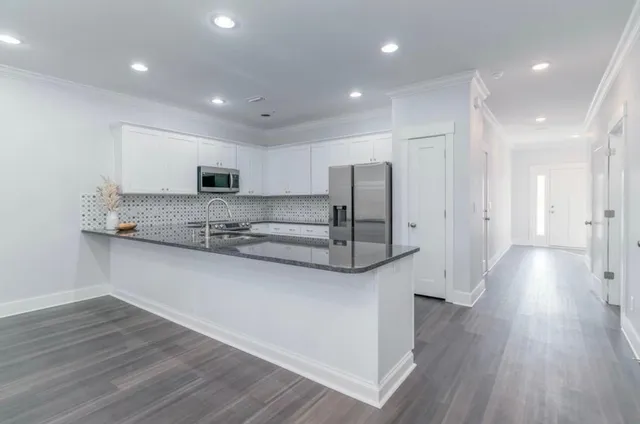 a large kitchen with stainless steel appliances a large counter top a stove and a wooden floors