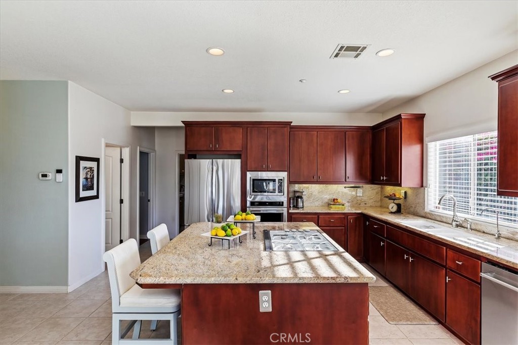 1260 Ransom Road Riverside, CA 92506 - Photo 18 of 50 a kitchen with a stove a sink a refrigerator a kitchen island with a dining table and chairs