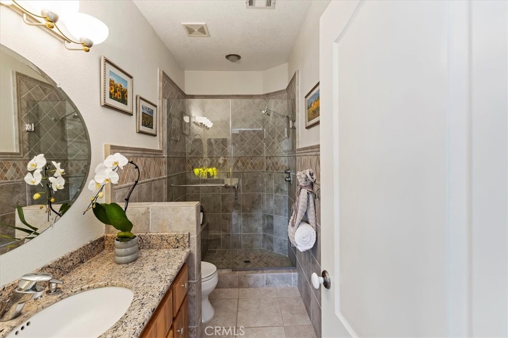 1260 Ransom Road Riverside, CA 92506 - Photo 25 of 50 a bathroom with a granite countertop sink a toilet and shower