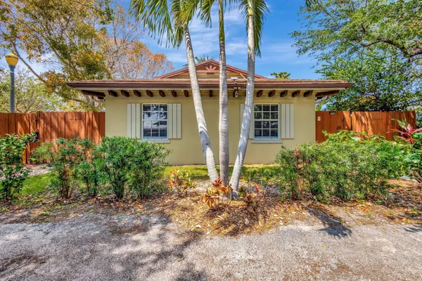 a front view of a house with a yard and potted plants
