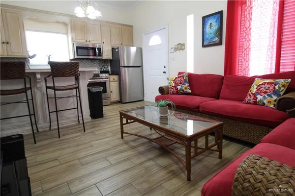 a living room with stainless steel appliances kitchen island granite countertop furniture and a wooden floor