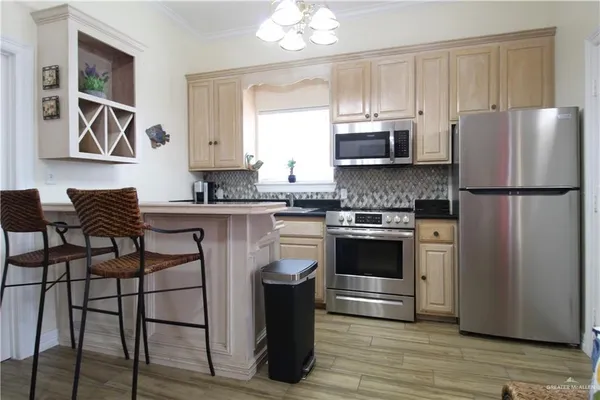 a kitchen with stainless steel appliances granite countertop a stove a refrigerator a microwave a sink and white cabinets with wooden floor