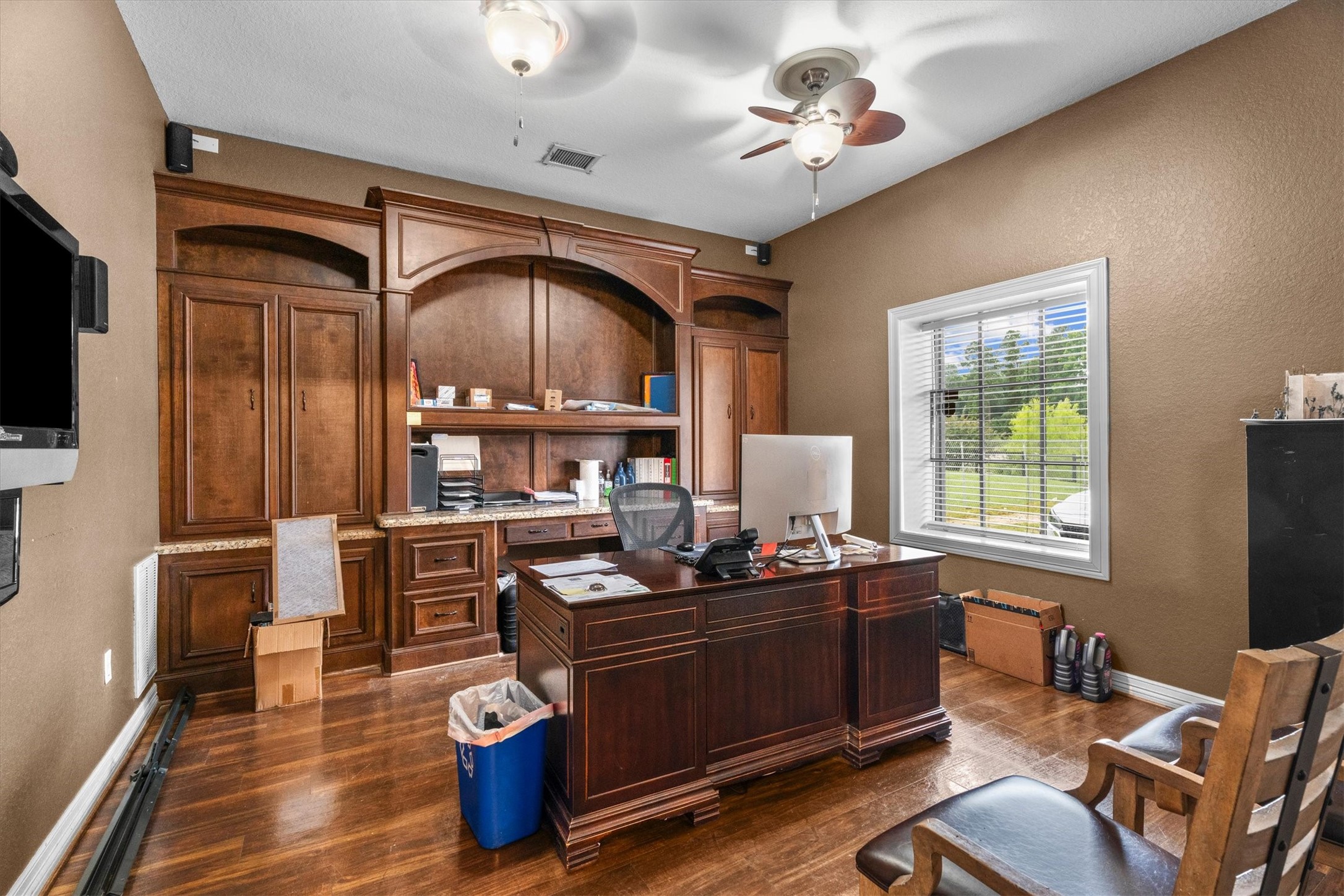 11066 Sh 242 Conroe, TX 77385 - Photo 13 of 21 This home office features rich wood cabinetry, a large built-in desk, and ample storage. A window provides natural light, and the room has a ceiling fan for comfort. Perfect for remote work or study.