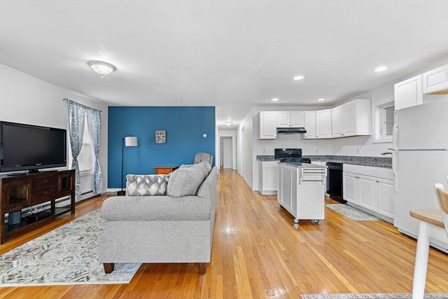 a living room with stainless steel appliances furniture and a flat screen tv