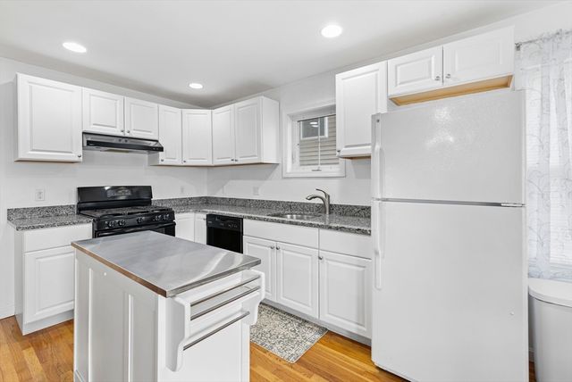 a kitchen with a sink a stove a refrigerator and white cabinets