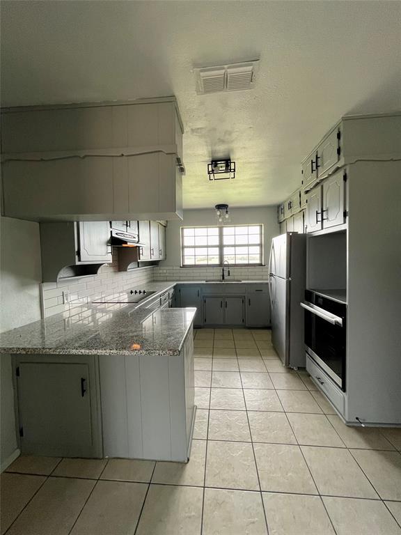 4203 Weiland Road Weatherford, TX 76088 - Photo 4 of 29 a kitchen with granite countertop a sink a counter top space appliances and cabinets