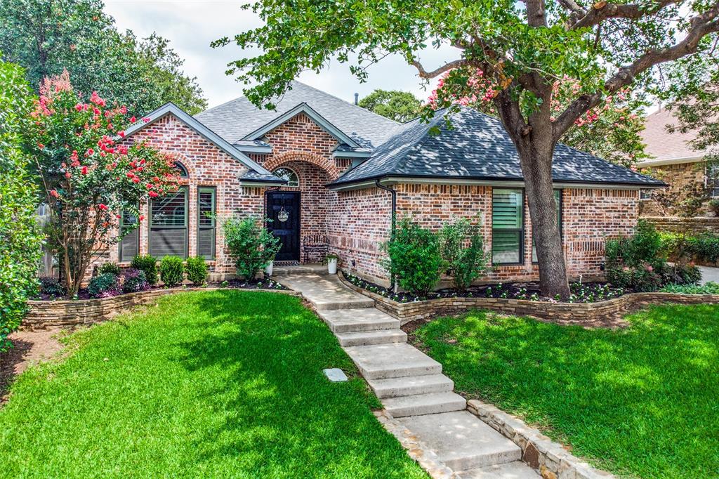 a view of a house with a small yard and a large tree