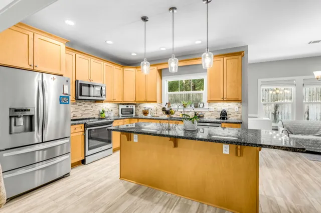 a kitchen with stainless steel appliances granite countertop a sink a stove and refrigerator