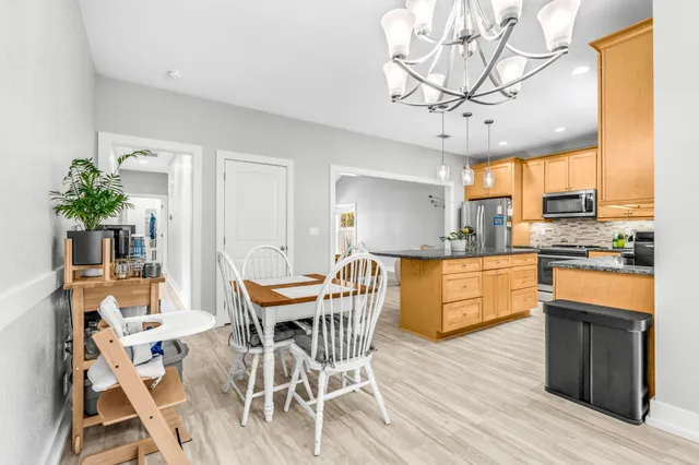 a kitchen with stainless steel appliances granite countertop wooden floor dining table and chairs