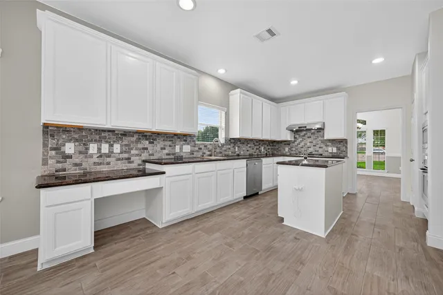 a kitchen with sink a white cabinets and window