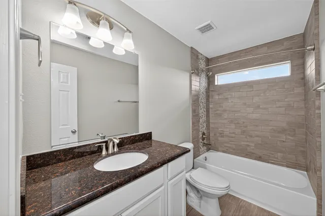 a bathroom with a granite countertop sink toilet mirror and shower
