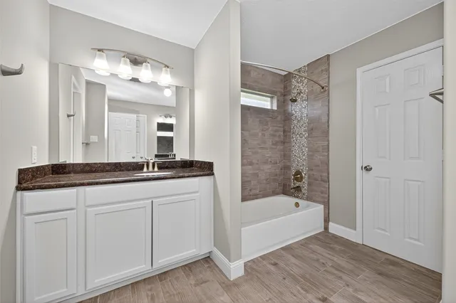a bathroom with a bathtub a double vanity sink and mirror