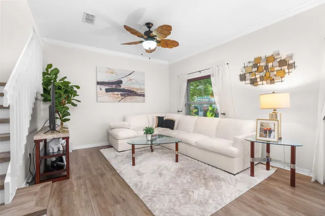 a living room with couches painting on the wall and a potted plant