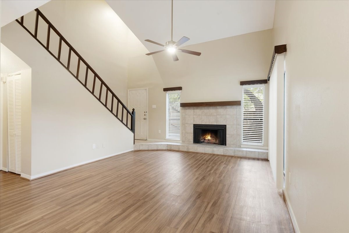 a view of an empty room with wooden floor fireplace and a window