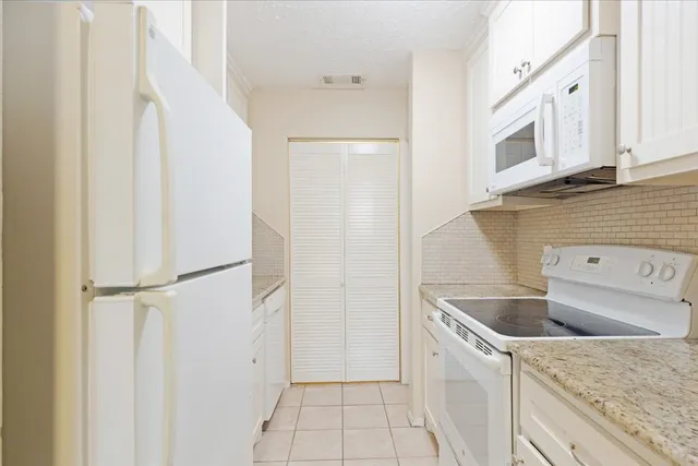 a view of a kitchen with white cabinets and a refrigerator