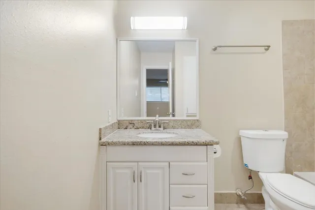 a bathroom with a granite countertop sink toilet and mirror