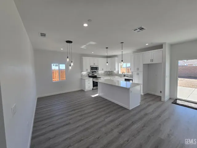 a large kitchen with stainless steel appliances granite countertop a large counter top and a wooden floors