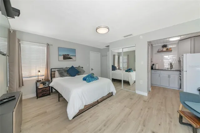 a bedroom with a bed a chair and potted plant on the dresser
