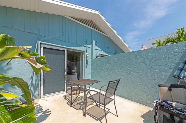 a patio with table and chairs and potted plants