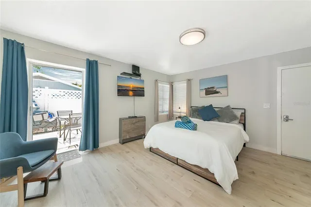 a spacious bedroom with a bed and a flat tv screen on the dresser