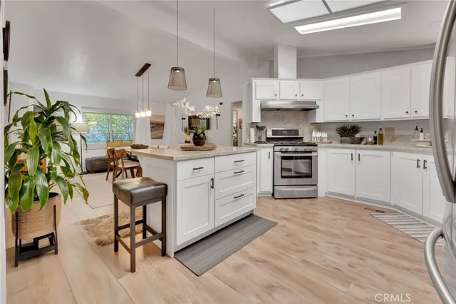 a kitchen with stainless steel appliances a stove a sink cabinets and a wooden floor