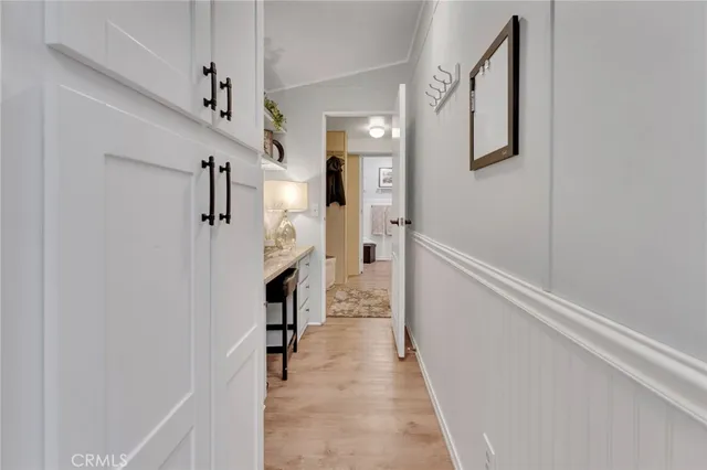 a hallway with white cabinets and chandelier