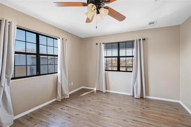 an empty room with wooden floor cabinet and windows