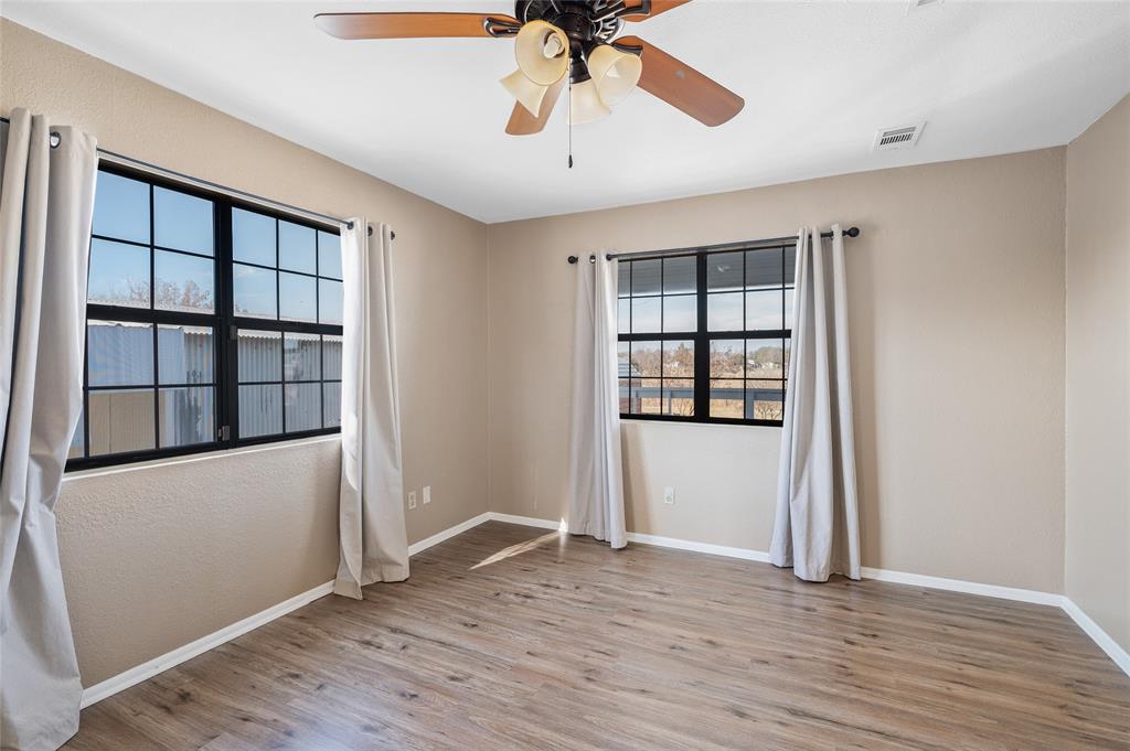 208 West Maple Street Gunter, TX 75058 - Photo 13 of 32 an empty room with wooden floor cabinet and windows
