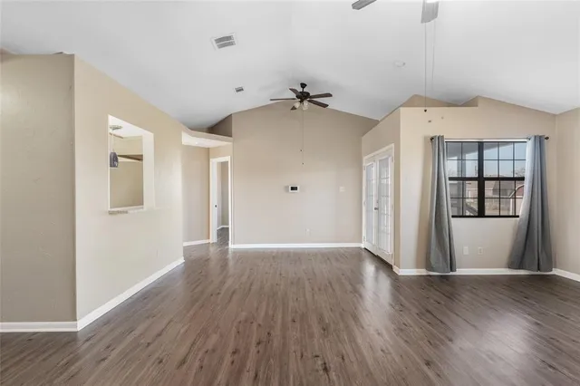 a view of an empty room with window and wooden floor