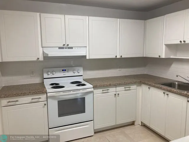a kitchen with granite countertop white cabinets and white appliances