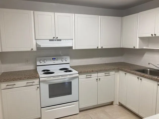 a kitchen with granite countertop white cabinets and white appliances
